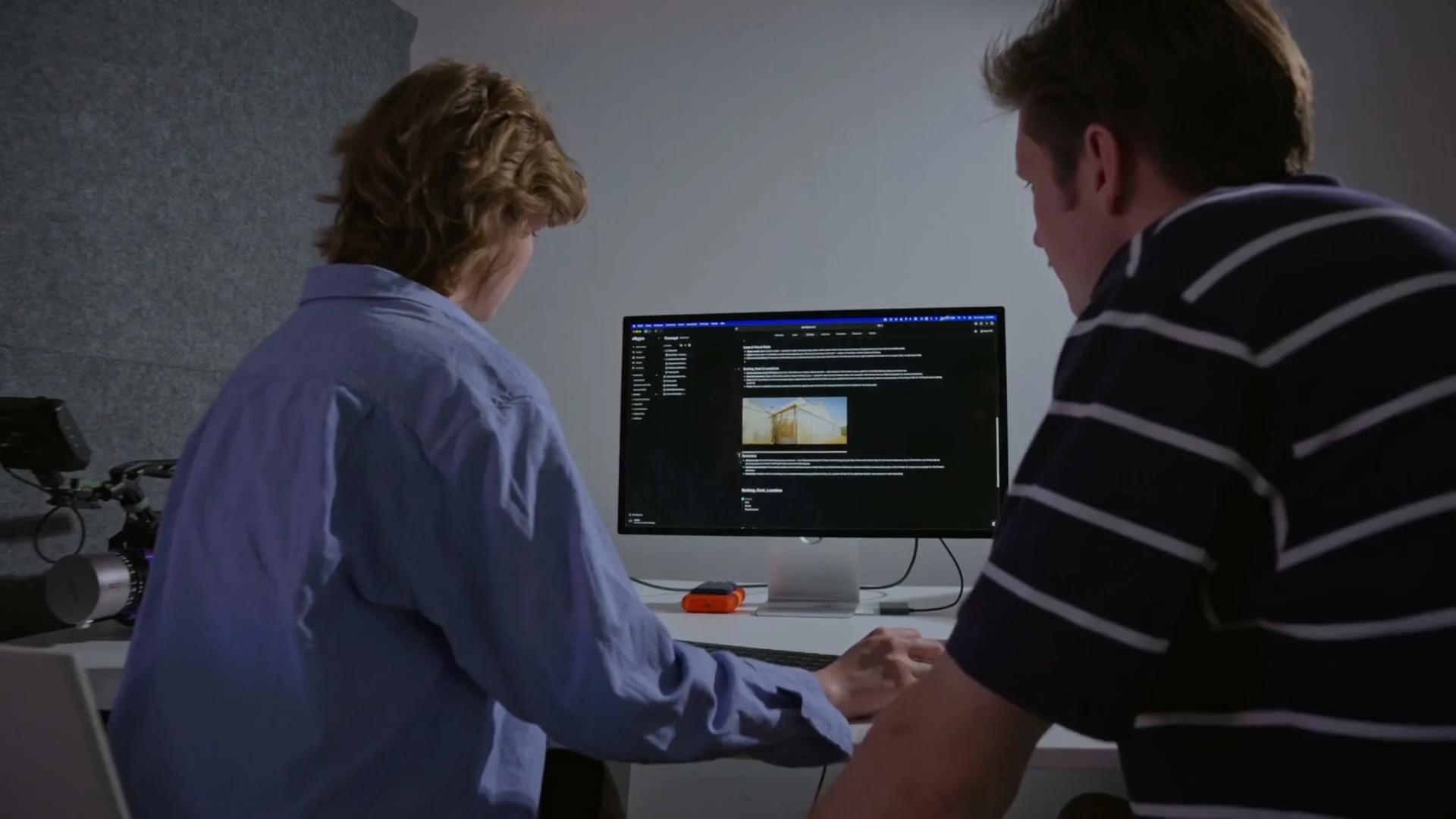 Two people at a desk going through a TillyBoard treatment with a reference image on a large monitor.